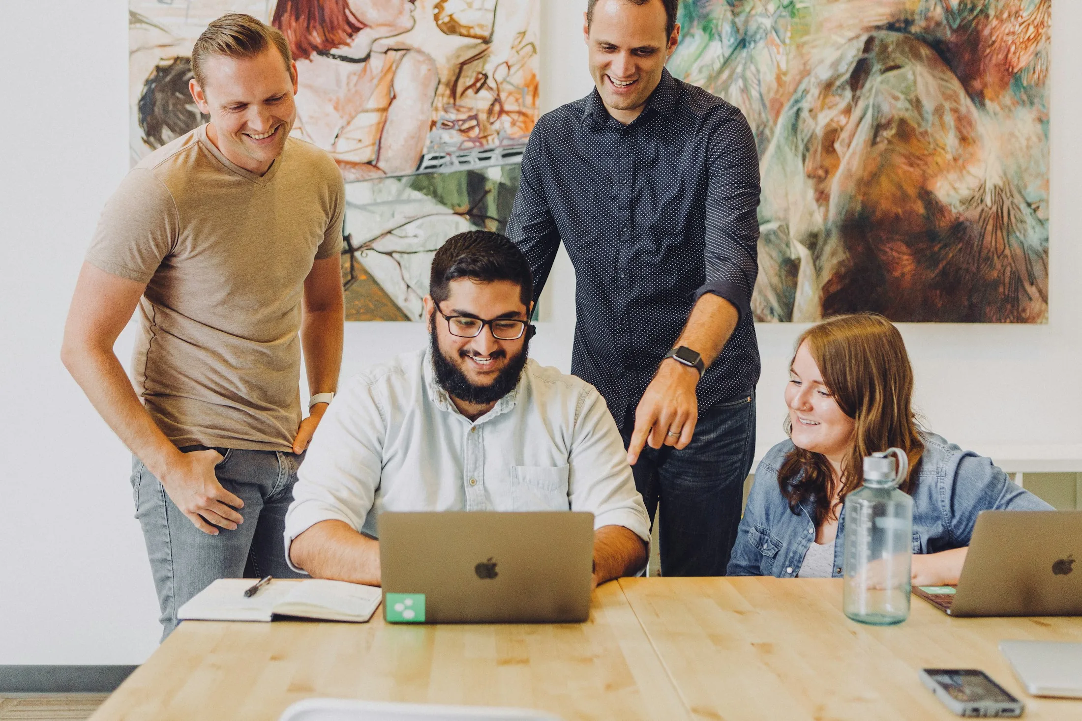 Equipe sorrindo e colaborando com notebooks em um escritório conectado